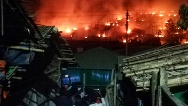 اشخاص تجمعوا لمشاهدة النيران مندلعة في مخيم للاجئين الروهينغيا في أوخيا في بنغلادش (9 ك2 2022، أ ف ب). 