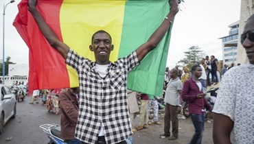 رجل يحمل العلم المالي خلال احتفاله مع آخرين في شوارع العاصمة باماكو (18 آب 2020، أ ب). 