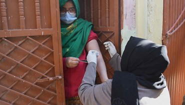 عاملة صحية تطعّم امرأة بلقاح كورونا في كراتشي (11 ك2 2022، أ ف ب). 