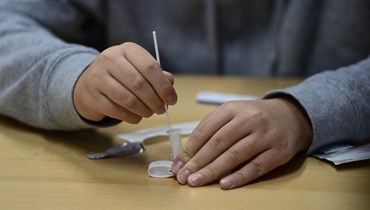 تلميذ يحمل عينة لإجراء اختبار سريع لفيروس كورونا (أ ف ب). 