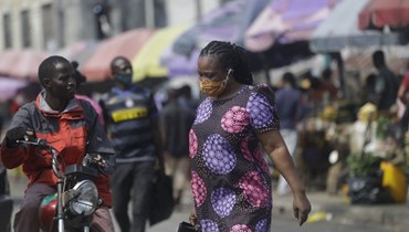 امرأة تمشي في أحد الأسواق في لاغوس بنيجيريا (24 ك1 2020، أ ف ب).