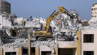 عمال فلسطينيون يستخدمون حفارًا لإزالة أجزاء من مبنى الجوهرة في حي الرمال في غزة، والذي تضرر في الغارات الجوية الإسرائيلية خلال ايار (16 ت2 2021، أ ب).