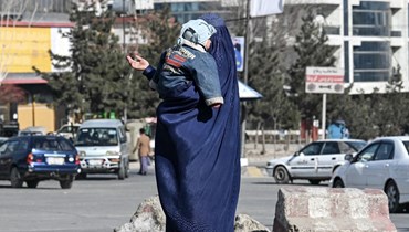 امرأة بالبرقع تتوسل وهي تحمل طفلاً في أحد شوارع كابول (14 ك2 2022، أ ف ب). 