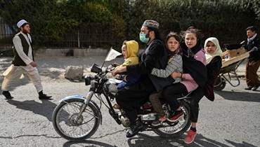 رجل يركب مع اطفال دراجة في أحد شوارع كابول (29 ك1 2021، ا ف ب). 