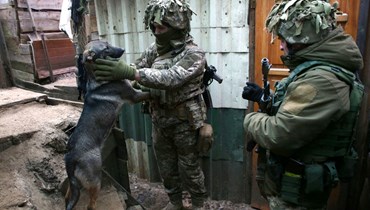 جندي أوكراني يداعب كلبًا في خندق على خط المواجهة مع الانفصاليين قرب أفدييفكا في دونيتسك  جنوب شرق أوكرانيا (9 ك2 2022، أ ف ب). 