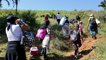 مهاجرون يعبرون من هندوراس إلى غواتيمالا عبر ممر غير شرعي في كورينتو بهندوراس (15 ك2 2022، ا ف ب). 