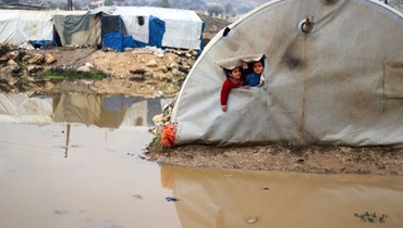 أطفال سوريون ينظرون من خيمتهم في مخيم البليع للنازحين بالقرب من مدينة جسر الشغور في محافظة إدلب شمال غرب سوريا (13 ك2 2022، أ ف ب).