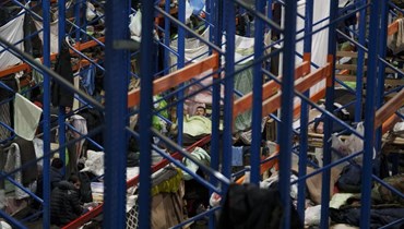 رجل يستعد للنوم، بينما استقر مهاجرون في مركز الخدمات اللوجستية لنقطة التفتيش "بروزجي" على الحدود بين بيلاروسيا وبولندا بالقرب من غرودنو في بيلاروسيا (23 ك1 2021، أ ب). 
