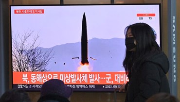 امرأة تمر قرب شاشة تلفزيون في محطة قطارات في سيول، تعرض مشاهد لاختبار صاروخ كوري شمالي (17 ك2 2022، أ ف ب). 