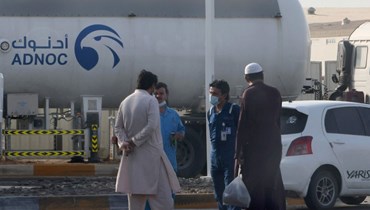 رجال وقفوا خارج منشأة تخزين تابعة لشركة النفط العملاقة أدنوك في أبوظبي (17 ك2 2022، أ ف ب). 