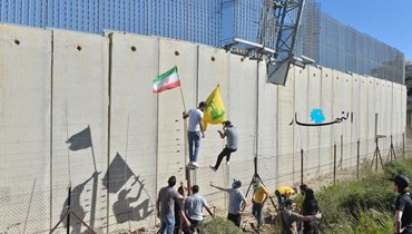 شبان من "حزب الله" يتسلّقون جدار الإسمنت الفاصل عند الحدود الجنوبية في كفركلا (نبيل إسماعيل).