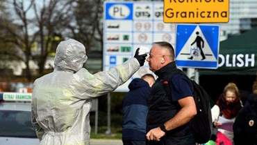 رجل يخضع لفحص درجة الحرارة على نقطة عبور الحدود بين بولندا وألمانيا (أ ف ب).