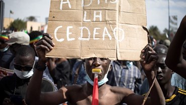 محتج حمل لافتة مناهضة لـ"إيكواس" خلال تظاهرة في باماكو (14 ك2 2022، أ ف ب). 