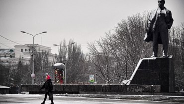 امرأة تمرّ بجانب تمثال لينين في دونيتسك في شرق أوكرانيا (18 ك2 2022، أ ف ب). 