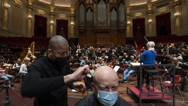 حلاق يقص شعر شخص خلال بروفة موسيقية على مسرح "كونسيرت خيباو" في أمستردام (19 ك2 2022، ا ب). 