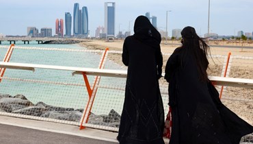 امرأتان تمشيان على الكورنيش البحري في أبوظبي (20 ك2 2022، أ ف ب). 