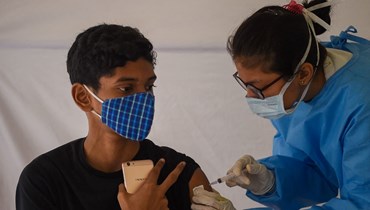 طالب يتلقى لقاح كورونا خلال حملة تطعيم في مومباي بالهند (22 ك2 2022، أ ف ب). 