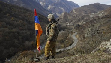 جندي أرميني يقف بجانب علم ناغورنو- كراباخ على قمة تلة بالقرب من تشاريكتار في منطقة ناغورنو كراباخ الانفصالية عند الحدود الجديدة مع مقاطعة كالباجار التي تم تسليمها إلى أذربيجان (25 ت2 2020، أ ب). 