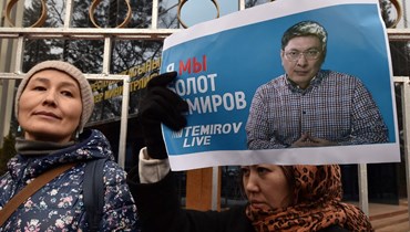 امرأة حملت صورة للصحافي بولوت تيميروف خلال تجمع في بيشكيك للمطالبة بإطلاقه (23 ك2 2022، أ ف ب). 