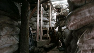 جندي أوكراني مع كلبه عند خط المواجهة مع الانفصاليين بالقرب من قرية زولوتي في منطقة لوغانسك الشرقية (21 ك2 2022، أ ف ب). 