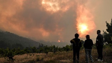 سكان يشاهدون حريق غابة بالقرب من قرية بيفكانياس غرب أثينا (20 ايار 2021، أ ف ب).