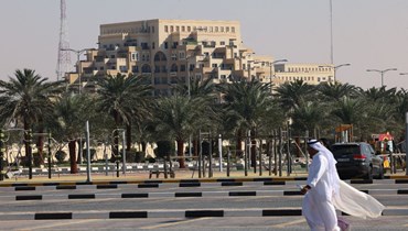 رجل يمشي في موقف للسيارات في جوار منتجع سياحي قرب جزيرة المرجان في إمارة رأس الخيمة في الإمارات (26 ك2 2022، أ ف ب). 