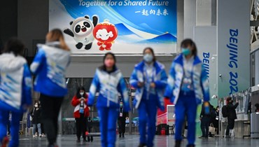 متطوعون في دورة الألعاب الأولمبية الشتوية في بيجينغ 2022 يمشون في المركز الصحافي الرئيسي في بيجينغ (28 ك2 2022، أ ف ب). 