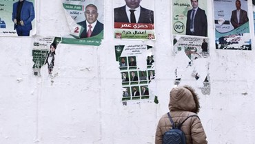 شخص يمر قرب ملصقات انتخابية في الجزائر العاصمة (25 ت2 2021، أ ب).