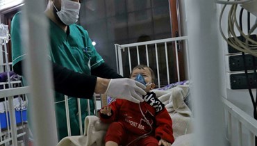 ممرض يثبت قناع الأوكسيجين على وجه طفل يتلقى الرعاية داخل أحد مستشفيات مدينة إدلب (أ ف ب).