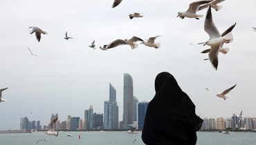 امرأة تطعم طيور النورس على كورنيش البحر في أبوظبي، عاصمة الإمارات، 20 كانون الثاني 2022 (أ ف ب).