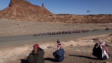 سكان محليون يشاهدون مرور متسابقين على الدراجات خلال المرحلة الثانية من الجولة السعودية، من العلا إلى أبو رقة (2 شباط 2022، أ ف ب). 