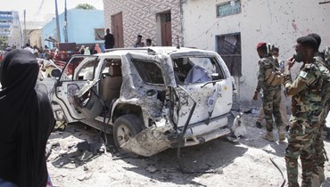 عناصر من قوات الأمن تجمعوا حول حطام سيارة تضررت في تفجير انتحاري في مقديشو (3 ك2 2022، أ ب). 
