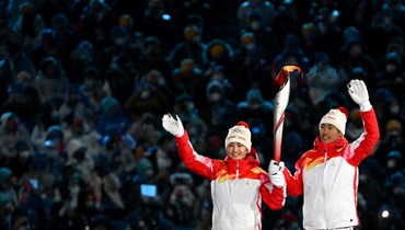 دينيجير يلاموجيانغ (الى اليسار) وتشاو جياوين يحملان الشعلة الأولمبية خلال افتتاح دورة الألعاب الأولمبية الشتوية بيجينغ 2022، في الاستاد الوطني في بيجينغ (4 شباط 2022، أ ف ب). 