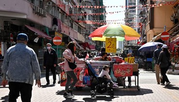 اشخاص يمرون قرب باعة متجولين في حي شام شوي بو في هونغ كونغ (4 شباط 2022، ا ف ب). 