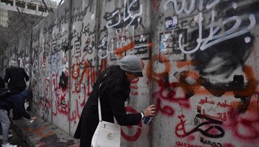 مواطنة تُعبّر عن رأيها وتكتب على حائط مصرف لبنان (حسام شبارو).