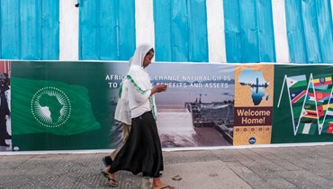 أشخاص يمرون قرب لافتة وضعت في أديس أبابا في إطار الاستعدادات في المدينة لاستضافة قمة الاتحاد الأفريقي (1 شباط 2022، أ ف ب). 