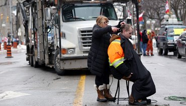 سائق شاحنة يقص شعره بينما يواصل متظاهرون الاحتجاج على قيود كورونا في أوتاوا بكندا (10 شباط 2022، ا ف ب). 