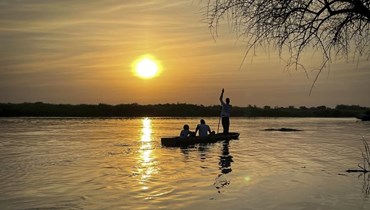 اشخاص ركبوا في زورق في فنجاك القديمة بولاية جونقلي جنوب السودان عند غروب الشمس (28 ك1 2021، ا ب). 