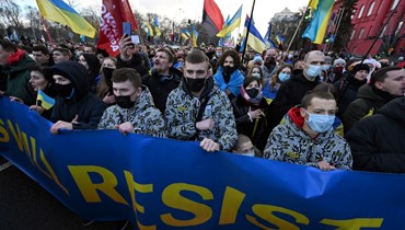 متظاهرون ساروا خلف لافتة كتب عليها "الأوكرانيون سيقاومون" خلال مسيرة في كييف (12 شباط 2022، أ ف ب). 