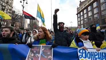 متظاهرون ساروا خلف لافتة كتب عليها "الأوكرانيون سيقاومون" خلال مسيرة في كييف (12 شباط 2022، أ ف ب). 