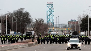 عناصر من الشرطة تجمعوا لاخلاء متظاهرين أغلقوا مدخل جسر امباسادور في وندسور بأونتاريو في كندا (13 شباط 2022، أ ف ب). 