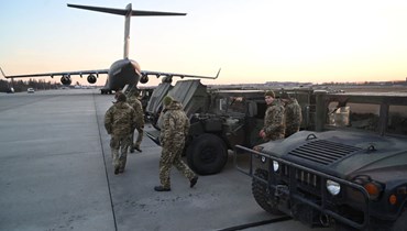 جنود أوكرانيون يفحصون شاحنات عسكرية تم شحنها من ليتوانيا إلى مطار بوريسبيل في كييف (13 شباط 2022، ا ف ب). 