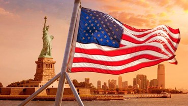 صورة العلم الأميركي وخلفه تمثال الحرية