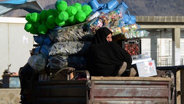 امرأة أفغانية استقلت شاحنة صغيرة تنقل خضراوات وحاويات بلاستيكية في قندهار (14 شباط 2022، أ ف ب)