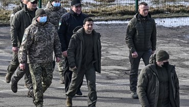زيلينسكي (في الوسط) لدى وصوله لحضور مناورة عسكرية خارج مدينة ريفنا شمال أوكرانيا (16 شباط 2022، أ ف ب). 