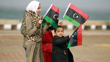 اطفال ليبيون يرفعون العلم الليبي خلال احتفالات في بنغازي شرق ليبيا في ذكرى الثورة على القذافي (17 شباط 2022، أ ف ب).