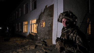 جندي أوكراني يقف بالقرب من الأنقاض بعد قصف طال روضة أطفال في أوكرانيا (أ ف ب- 17 شباط 2022).