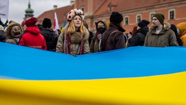 متظاهرون يلوحون بالأعلام الأوكرانية والبولندية خلال تظاهرة في وارسو من أجل السلام في أوكرانيا (20 شباط 2022، أ ف ب). 
