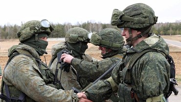 جنود روس (إلى اليسار) وبيلاروسيون (الى اليمين) يتصافحون خلال تدريبات مشتركة في ميدان تدريب بالقرب من بريست (19 شباط 2022، أ ف ب). 