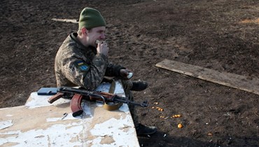 جندي أوكراني يتناول وجبة إفطار في موقع على خط المواجهة مع الانفصاليين بالقرب من نوفوهناتيفكا بمنطقة دونيتسك (20 شباط 2022، ا ف ب). 